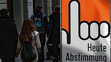 Archivbild: Menschen in der Schweiz passieren einen Aufsteller mit dem Schriftzug &ldquo;Heute Abstimmung&bdquo;, der auf ein Referendum ...
