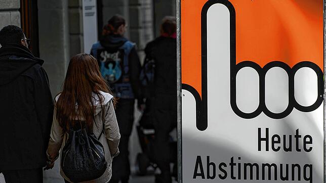 Archivbild: Menschen in der Schweiz passieren einen Aufsteller mit dem Schriftzug &ldquo;Heute Abstimmung&bdquo;, der auf ein Referendum ...