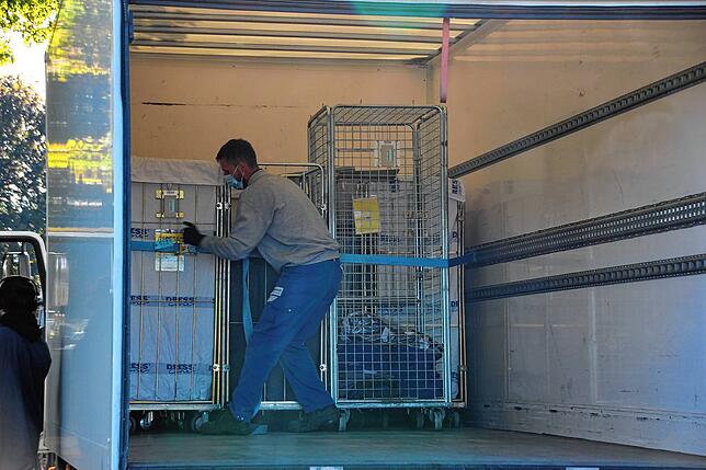 Der Fahrer eines Wäschetransporters muss einen Teil seiner Ladung mit Spanngurten nachsichern.
