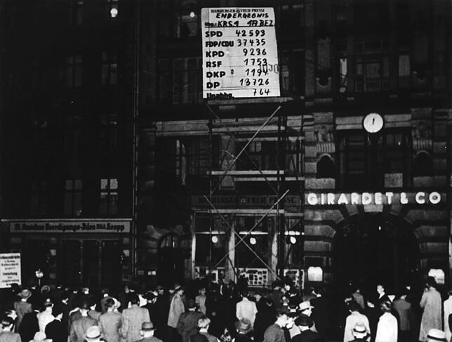 Vor einer großen Tafel warten in den Abendstunden des 14. August 1949 Bürger auf die Bekanntmachung der neuesten Ergebnisse der ...