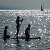 Drei Kinder sind im Bodensee auf einem SUP unterwegs.