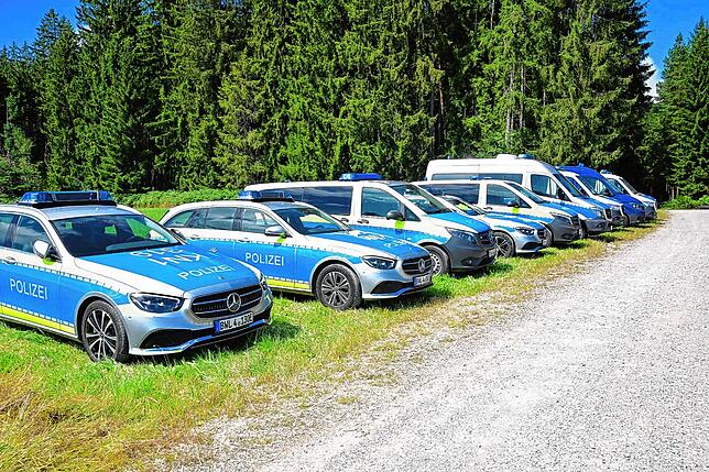 Einsatzfahrzeuge stehen aufgereiht am Waldrand.