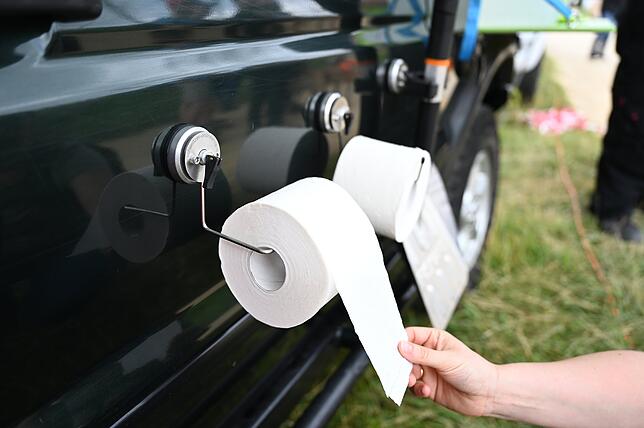 Eine Messebesucherin zieht bei der Survival- und Outdoor-Messe an einer Toilettenpapierrolle, die an einem Saugnapf befestigt ist, der ...