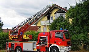 Eine Drehleiter steht vor dem Brandhaus. Oberhalb der Balkontüre hat das Feuer deutliche Rußspuren hinterlassen.
