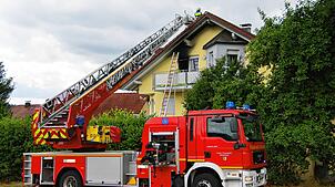 Eine Drehleiter steht vor dem Brandhaus. Oberhalb der Balkontüre hat das Feuer deutliche Rußspuren hinterlassen.