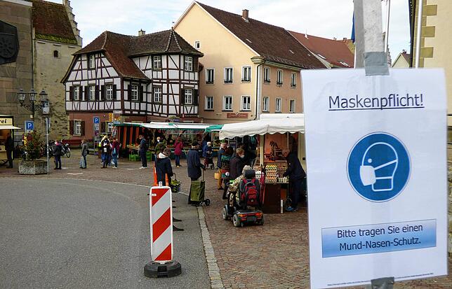 Szene vom Markdorfer Wochenmarkt. Vor dem Marktareal weist ein laminierter Aushang im Oktober 2020 auf die Maskenpflicht hin, eine Folge ...