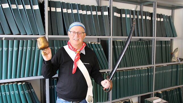 Mit Säbel und Glocke: Hubert &bdquo;Hubsi&ldquo; Reiser vor den Archivbänden des SÜDKURIER in der Stockacher Lokalredaktion. Der ...