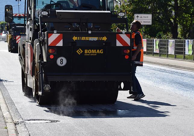 Hier ist nochmal die Walze zu sehen. Der heiße Asphalt dampft.