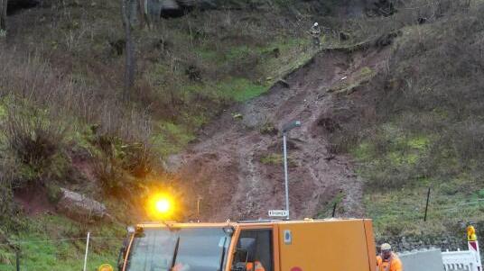 Am Tag danach: Bauhofmitarbeiter reinigen die Straße nach dem Hangrutsch an der Ecke Rochus-Merz-Straße/Burgweg. Bild: Martin Himmelheber