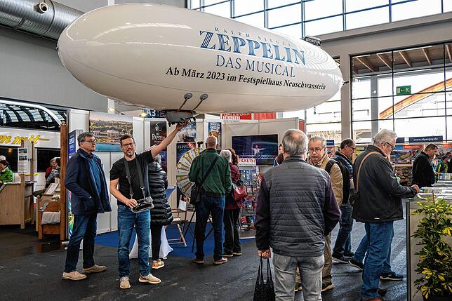 Joe Orszulik lässt in Halle A3 einen Zeppelin fliegen und wirbt für das gleichnamige Musical.