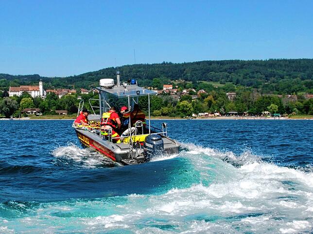 Das DLRG Rettungsboot fährt mit dem verletzten Wassersportler an das Öhninger Strandbad (inten links). Dort werden die Rettungskräfte ...
