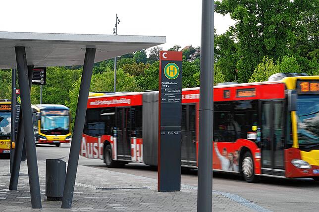 Zwei Busse fahren an einem haltenden Bus am Busbahnhof in Tübingen vorbei.