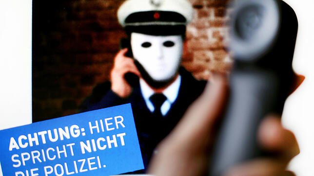 ARCHIV – 11.10.2017, Nordrhein-Westfalen, Düsseldorf: Ein Telefonhörer ist vor einem Plakat der Polizei NRW mit der Aufschrift «Achtung: ...
