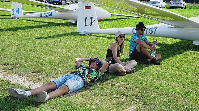 Die jungen Fliegerinnen und Flieger suchen in kleinen Gruppen Schatten unter den Flügeln ihrer Flugzeuge, während sie darauf hoffen, ...