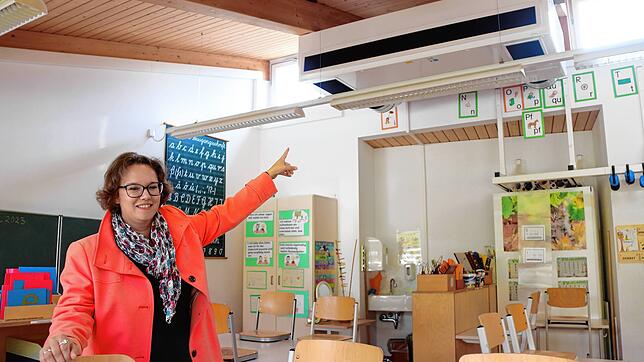 Carmen Kindler, kommissarische Schulleiterin der Grundschule Nußdorf, zeigt auf ein stationäres Lüftungsgerät in einem Unterrichtsraum.