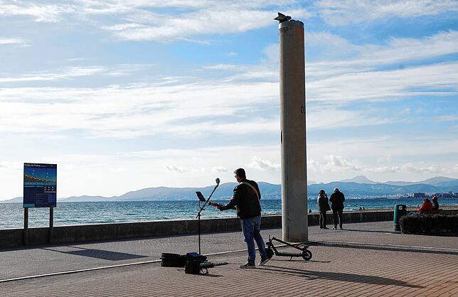 Ein Mann musiziert mit seiner Gitarre auf der Promenade am Strand von El Arenal auf Mallorca. Reisen auf die Insel sind trotz ...