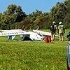 Die Feuerwehrleute untersuchen das Ultraleichtflugzeug, das durch den Unfall auf das Dach gedreht wurde.
