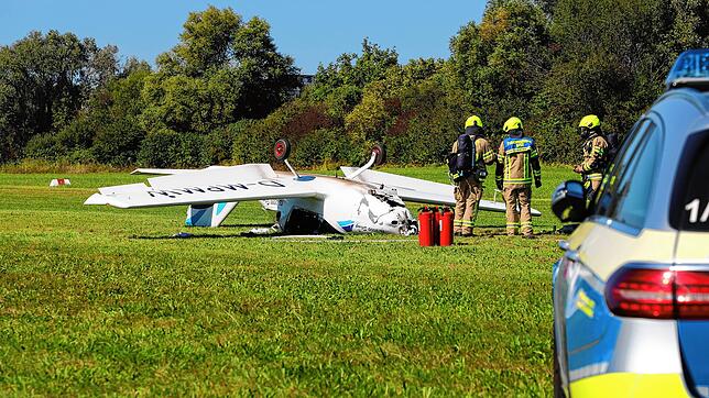 Die Feuerwehrleute untersuchen das Ultraleichtflugzeug, das durch den Unfall auf das Dach gedreht wurde.