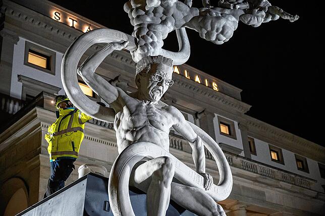 Ein Arbeiter steht neben der Statue.