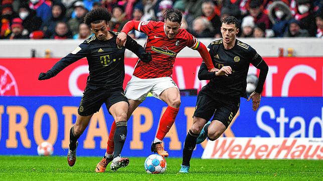 Bayerns Leroy Sane (l) kämpft mit Freiburgs Christian Günter (M) und Bayerns Benjamin Pavard um den Ball.