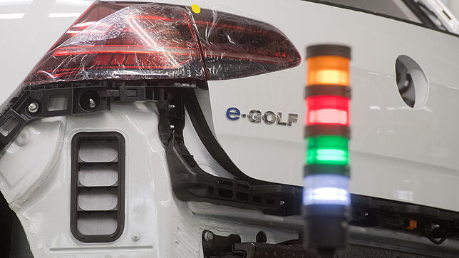 Eine Ampel leuchtet neben einem VW E-Golf im Volkswagen Werk. Das Auto ist bislang ein Ladenhüter.