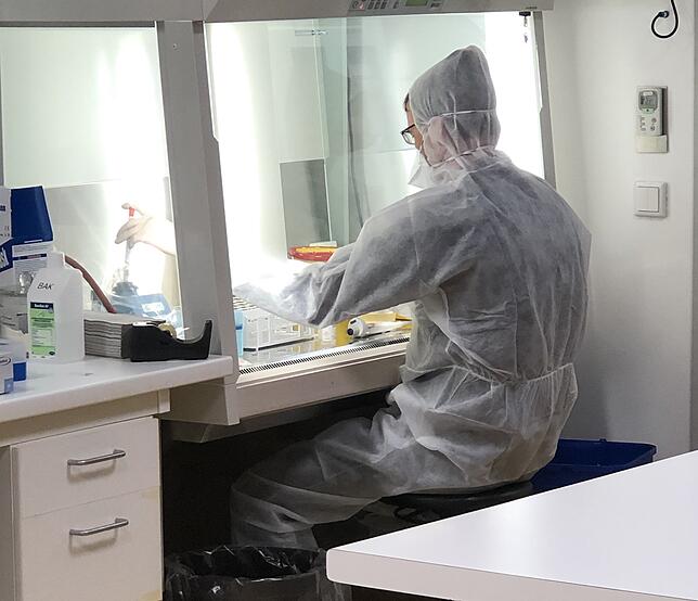 Der Molekularbiologe Dr. Lars Steinmüller-Magin öffnet eine Probe und behandelt die Viren vor, indem er die Virus-Hüllen unschädlich macht.