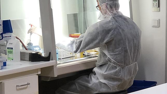 Der Molekularbiologe Dr. Lars Steinmüller-Magin öffnet eine Probe und behandelt die Viren vor, indem er die Virus-Hüllen unschädlich macht.