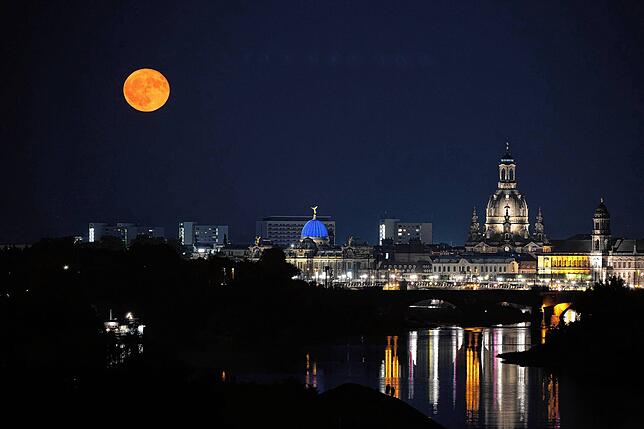 Passanten beobachten am 11. Juni in Dresden am Ufer der Elbe den Aufgang des Erdbeermondes.