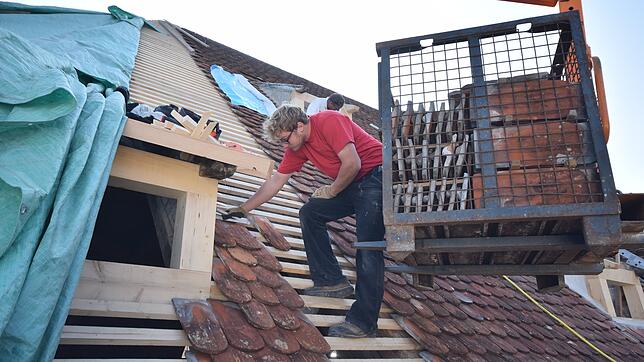 Ralf Kurz von der Firma Hummel deckt das Dach wieder mit Biberschwanzziegeln ein.