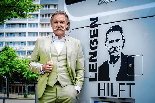 Ingo Lenßen links in echt, rechts auf einem Bus, der durch Berlin fährt.