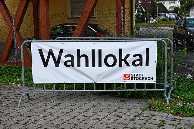 Große Banner wie dieses weisen auf Wahllokale hin. Dieses hier steht beim Parkplatz des Wahllokals neben der Tafel in der ...