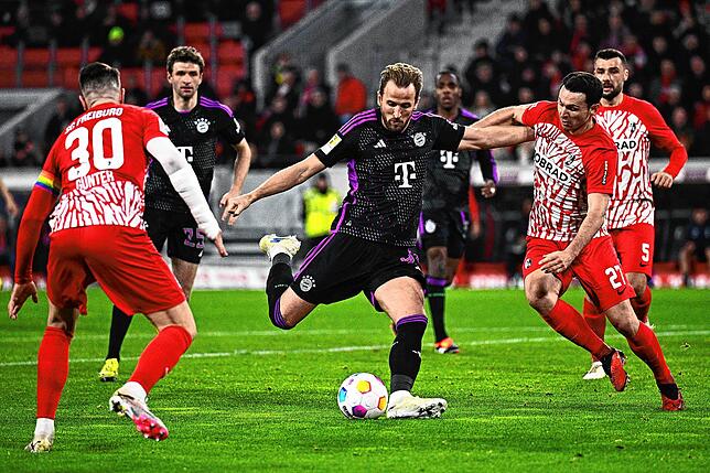 Münchens Harry Kane (M) in Aktion gegen Freiburgs Nicolas Höfler und Christian Günter (l).