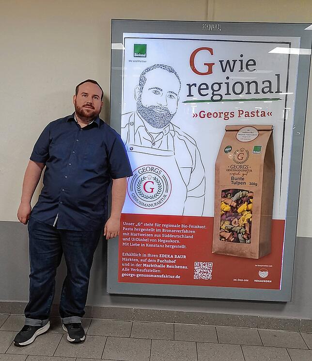 Georg Schönberger vor einem Plakat mit seiner Abbildung bei Edeka Baur in Konstanz. Von Freunden und Bekannten wurde er schon auf die ...