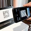 So läuft die Nutzung der Luca App. Ein Mann checkt sich bei einem gewerblichen Anbieter ein, indem er den QR-Code des Geschäfts mit ...