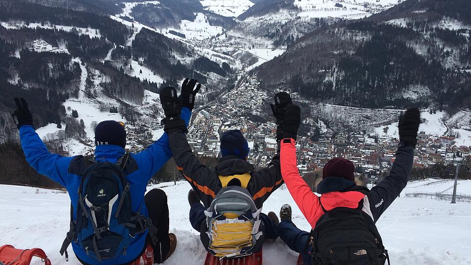 Diese drei Rodler freuen sich über die grandiose Aussicht auf die verschneite Landschaft an der Hasenhorn-Winterrodelbahn in Todtnau.