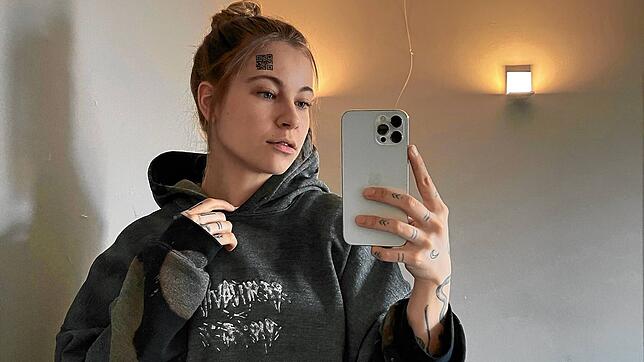 Influencerin Melina Sophie zeigt sich mit einem scheinbar auf die Stirn tätowierten QR-Code.