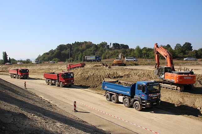Ein Bagger verlädt Erde auf die wartenden LKW auf der Baustelle zur neuen B31.