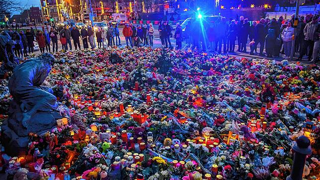 Magdeburg: Menschen stehen vor der Johanniskirche an dem ein Gedenkort eingerichtet wurde und an dem vor dem Portal Blumen und Kerzen ...