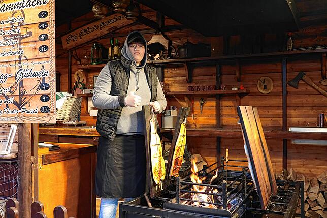 Abd Allah Doumani wärmt sich an der Feuerstelle am Flammlachs-Stand.