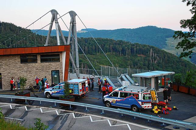 Bergretter mit ihren Einsatzfahrzeugen stehen an der Hängebrücke bereit.