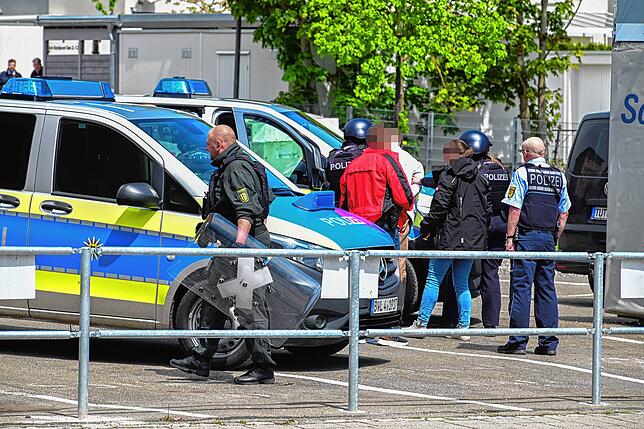 Die Hände des Mannes sind auf dem Rücken fixiert. Im Vordergrund ein Polizist mit Schutzschild.