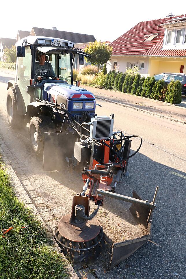 Der Wildkrautbesen fräst den Bewuchs vom Straßenrand.