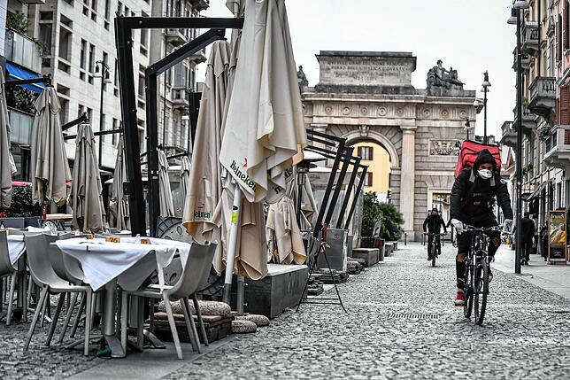 Italien, Mailand: Ein Fahrradfahrer eines Lieferdienstes fährt mit Mundschutz als Maßnahme gegen die Verbreitung des Coronavirus durch ...