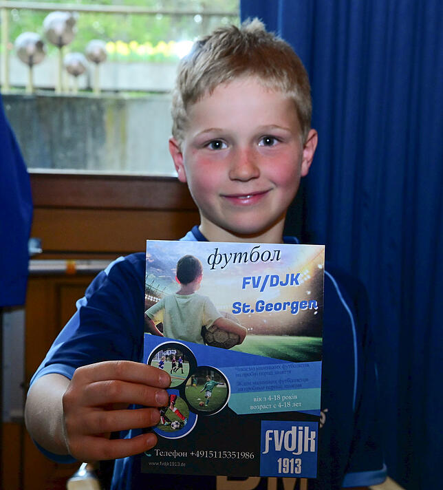 Jugendspieler Jonas Heller mit einem Flyer des Fußballverein FV/DJK, der auf Ukrainisch um Nachwuchsspieler wirbt.