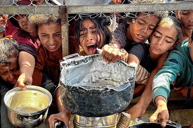 Die Hungersnot in den palästinensischen Gebieten ist groß: Kinder in Chan Junis versuchen, mit ihren Töpfen Nahrungsmittel zu bekommen, ...