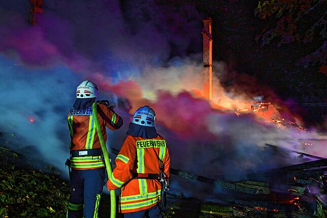 Die Einsatzkräfte versuchen, umliegende Gebäude und Bäume vor einem Übergreifen der Flammen zu schützen.