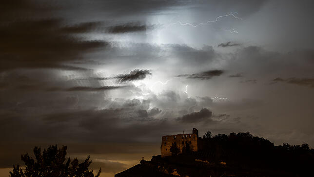 Blitze eines über das Elsass und Südbaden ziehenden Gewitters zeichnen sich hinter der Ruine der Burg von Staufen im Breisgau am Himmel ab.