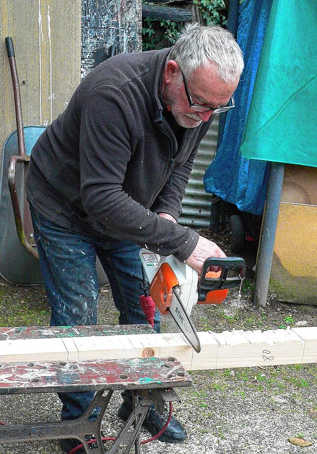 Mit der kleinen Kettensäge bearbeitet Josef Briechle die Einkerbungen in einem vorbereiteten Holzbalken.