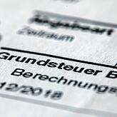 Ein Abgabenbescheid für die Entrichtung der Grundsteuer liegt auf einem Schreibtisch.