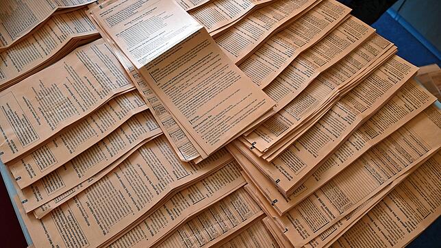 Stapelweise Wahlzettel zum Erfassen liegen auf Tischen im Rathaus.
